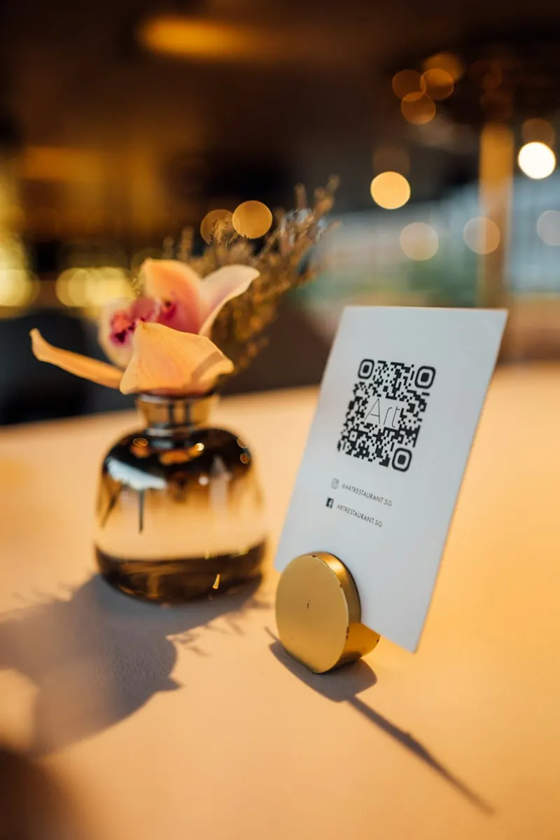A QR code table stand next to a vase
